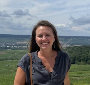 Woman enjoying wine tasting outdoors with scenic vineyard background.