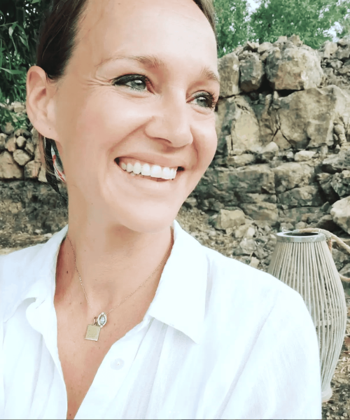Woman smiling outdoors with natural background, promoting inner journey and self-discovery.