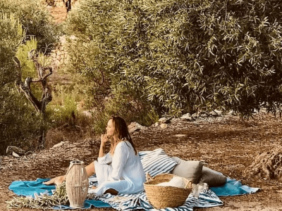 Outdoor picnic setup with a woman enjoying nature under a large tree.