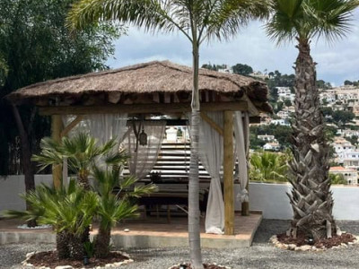 Outdoor yoga space with palm trees and shaded gazebo for wellness practices.